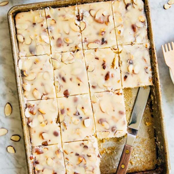photo of a white texas sheet cake in a 9 x 13 inch pan on marble table with slices removed
