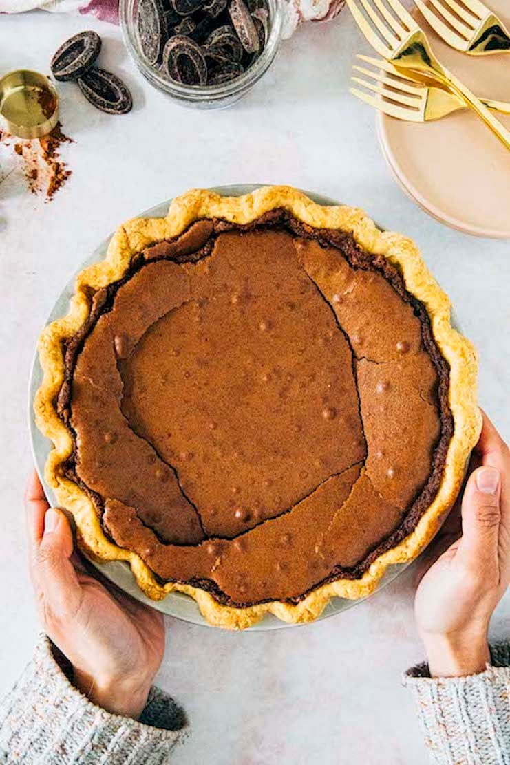 a photo of hands setting down a chocolate chess pie