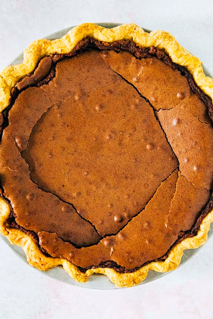 a close up photo showing a chocolate chess pie with cracks in its filling