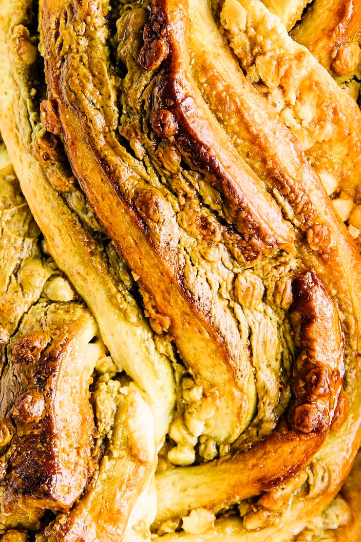 A close up photo of the top of the white chocolate pistachio babka showing its golden, toasted colors and texture. 