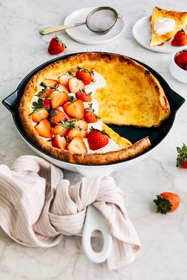 A photo of my best Dutch baby pancake recipe with a slice taken out of it.