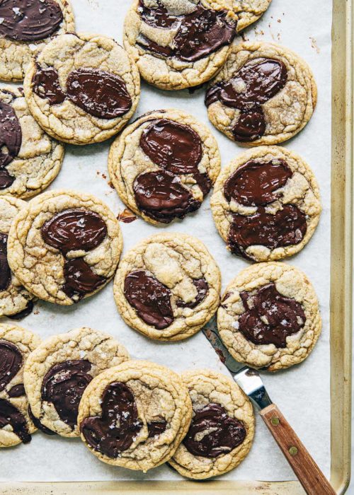 A photo of chocolate chip cookies on a gold sheet pan.