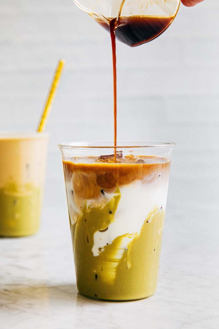 A picture showing a shot of espresso being poured into an iced pistachio latte drink.