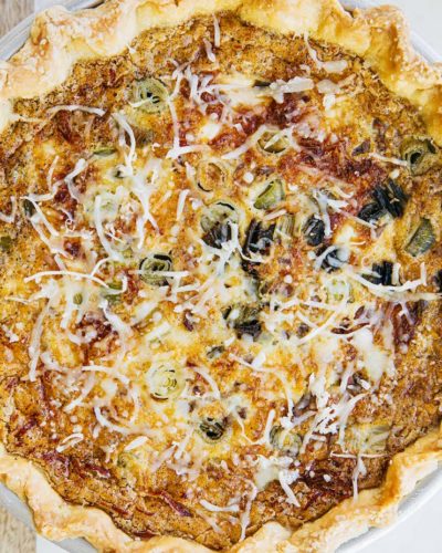 A close up photo of a quiche with a cheesy top.