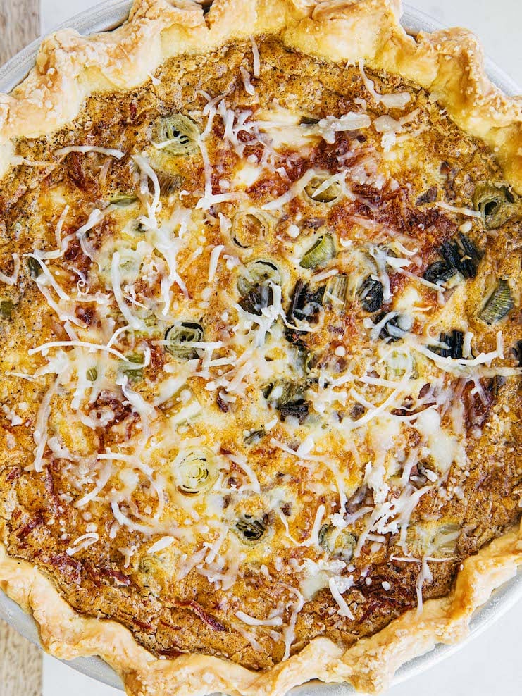 A close up photo of a quiche with a cheesy top.