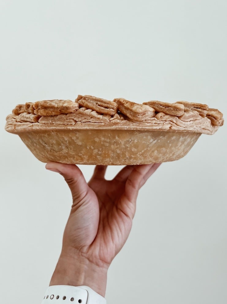 photo of a hand holding an entire pie without its pan