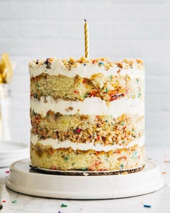 photo of milk bar birthday cake on white plate against white brick backdrop