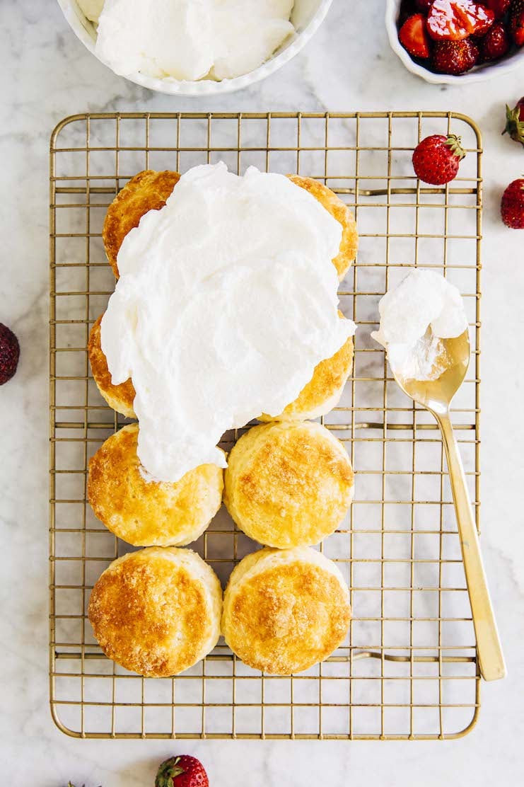 photo of biscuits on a wire rack partially topped with whipped cream with a spoon next to them