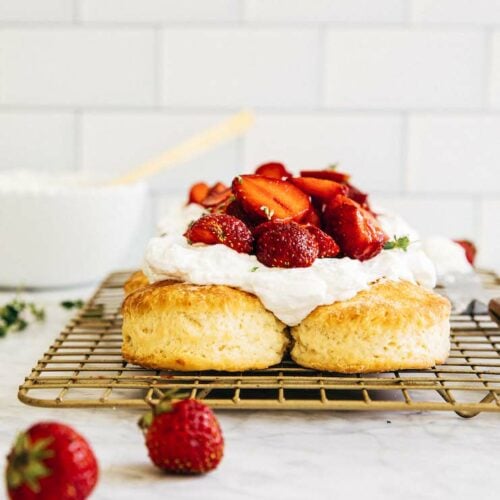 picture of biscuits on a gold wire rack topped with whipped cream and strawberries