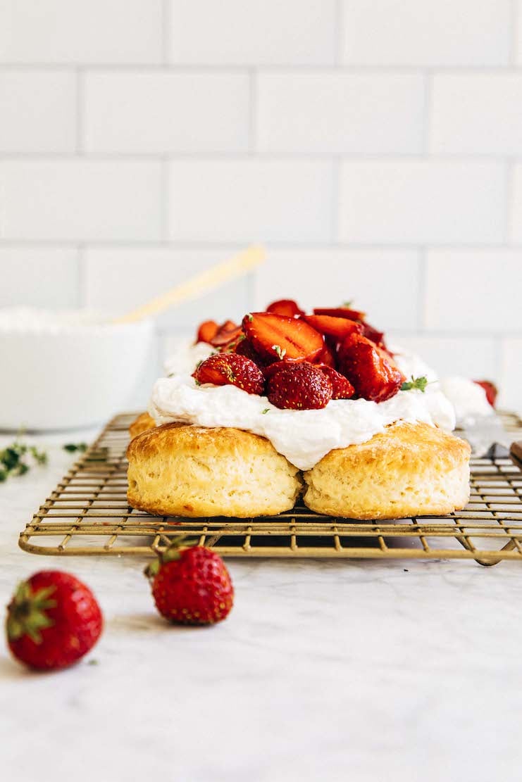picture of biscuits on a gold wire rack topped with whipped cream and strawberries