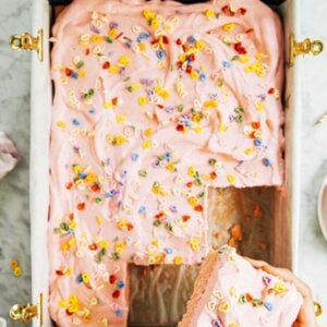 photo of pink sheet cake with hand holding up a slice of cake