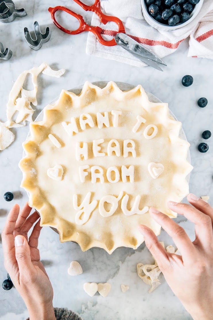 photo of unbaked pie reading "i want to hear from you" with hands arranging the letters