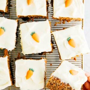 hand holding slice of carrot cake over wire rack
