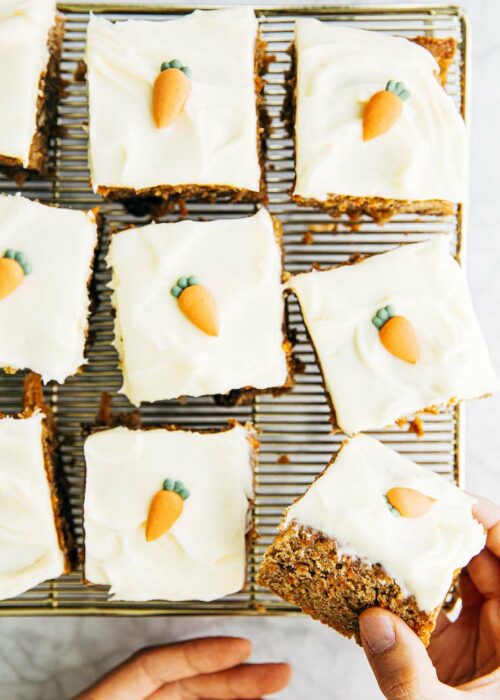 hand holding slice of carrot cake over wire rack