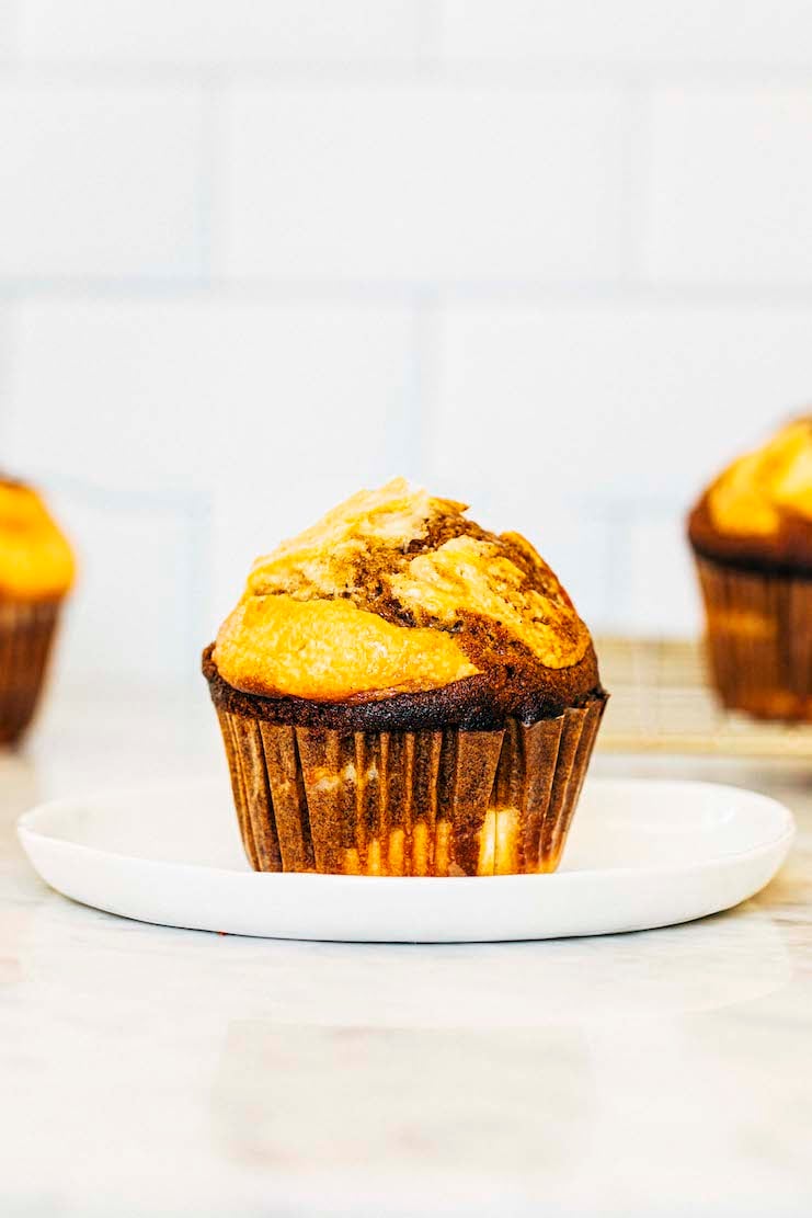 photo of pumpkin cream cheese muffin on white plate against white background
