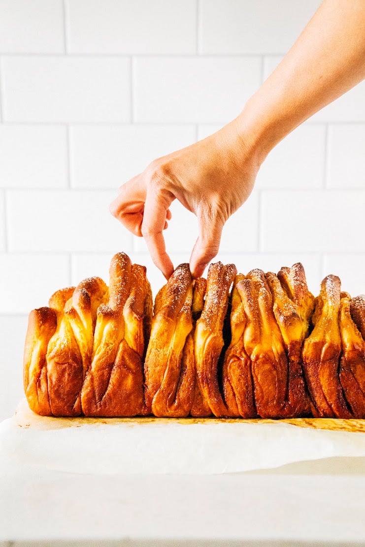photo of hand reaching for a slice of pumpkin pull apart bread