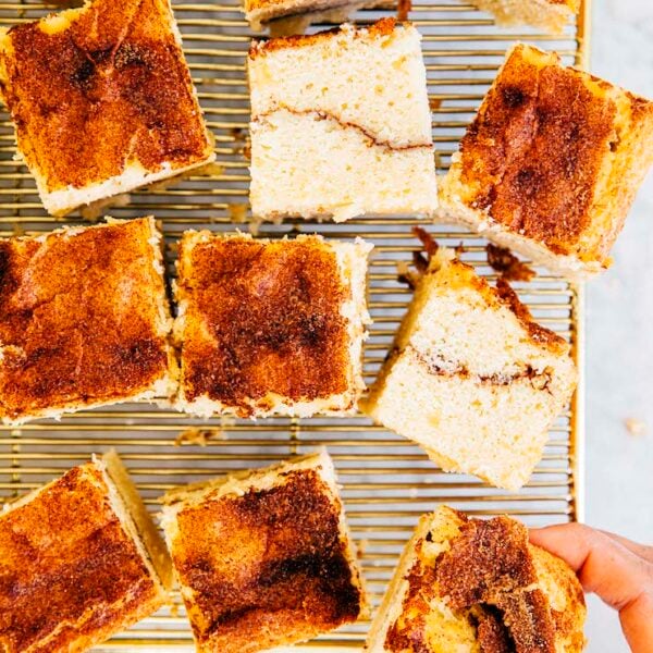 close up photo of hand reaching for a slice of snickerdoodle cake