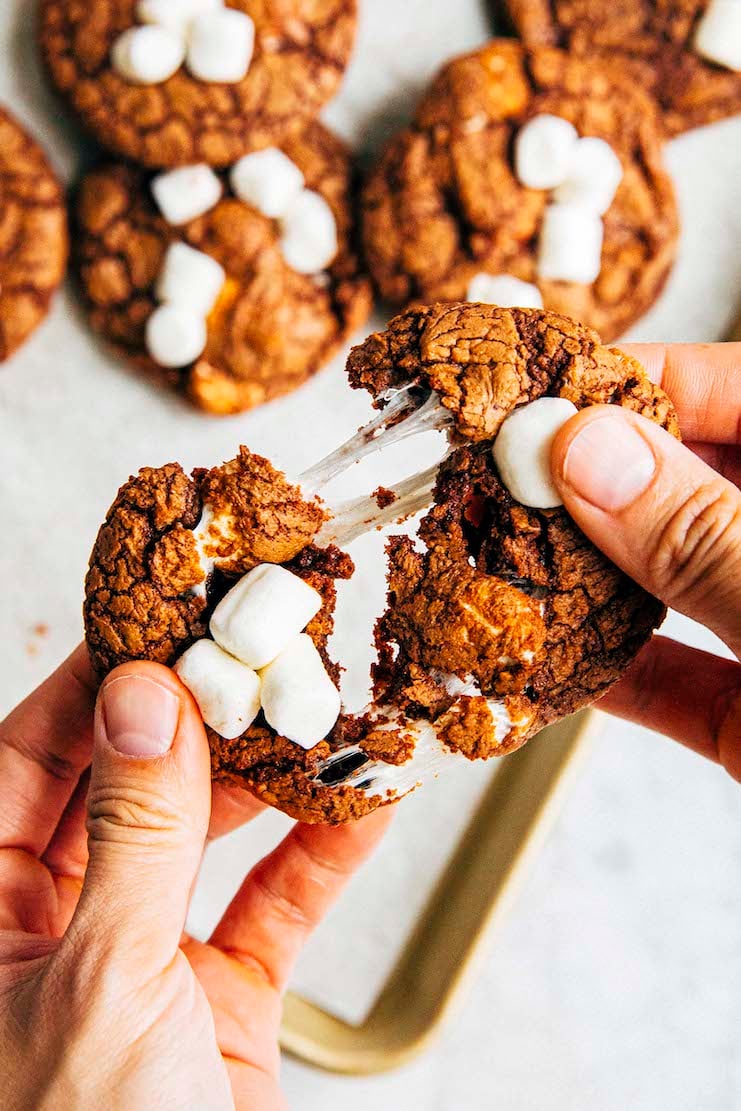 photo of hands pulling apart a single hot cocoa cookie showing marshmallow strands