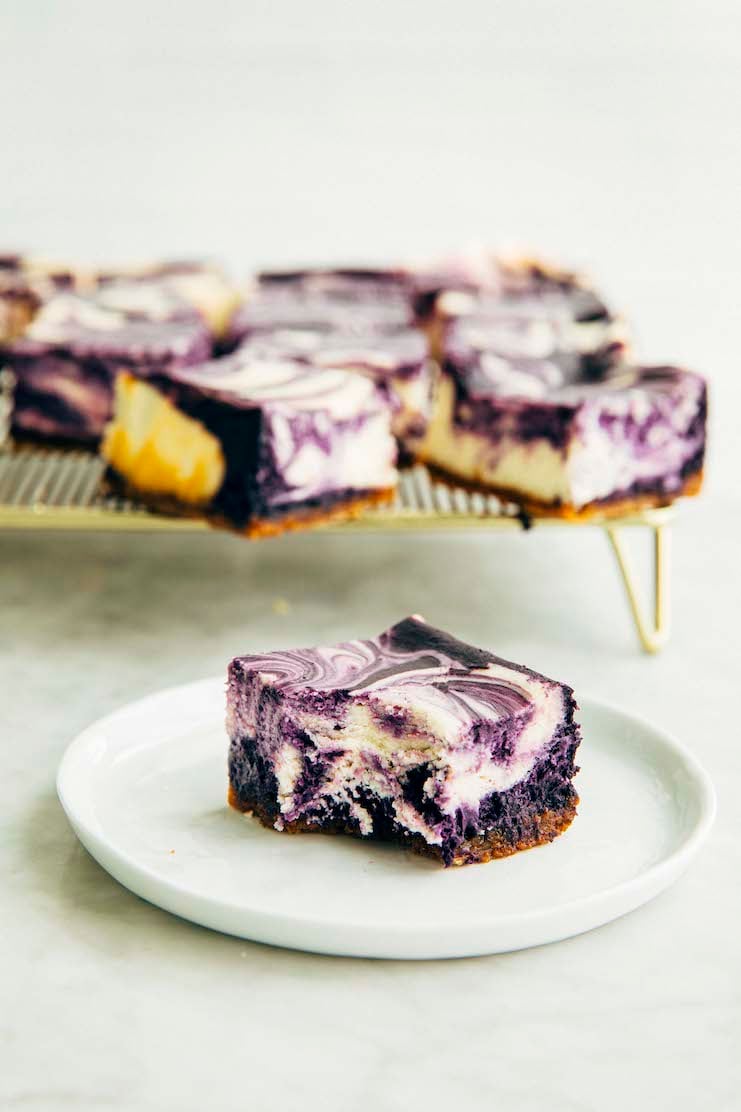 photo of ube cheesecake bar with a bite taken out of it on a small white plate