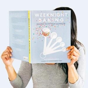 Michelle holding Weeknight Baking cookbook covering her face.