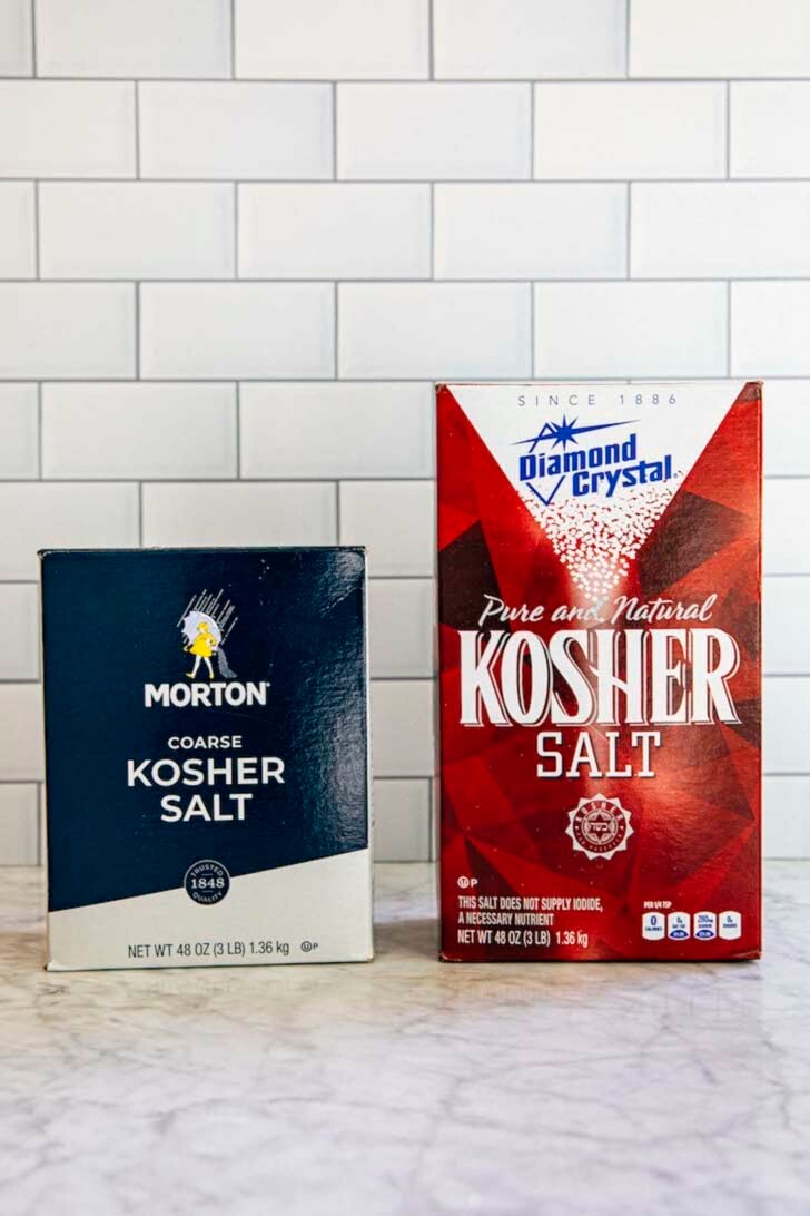photo showing a box of morton kosher salt and a box of diamond crystal kosher salt against a subway tile backdrop