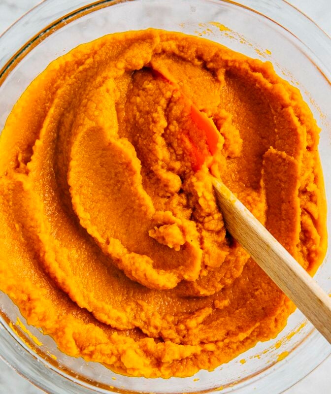 photo of homemade pumpkin puree in a clear bowl with a rubber spatula