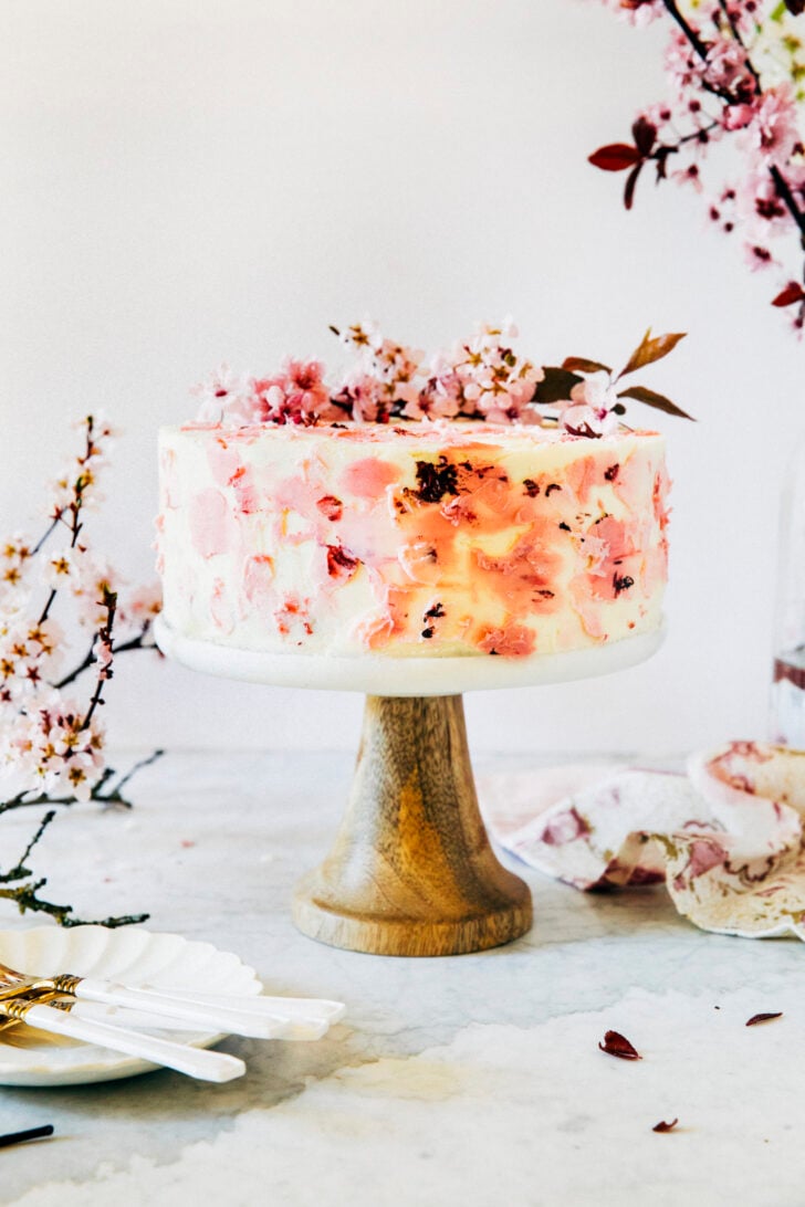 photo of cherry blossom cake on cake stand with wooden pedestal