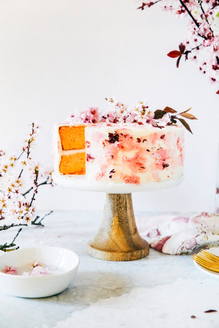 photo of cherry blossom cake with one slice taken out on cake stand