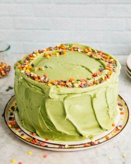 photo of the pistachio pudding layer cake on a marble tabletop against a white brick background