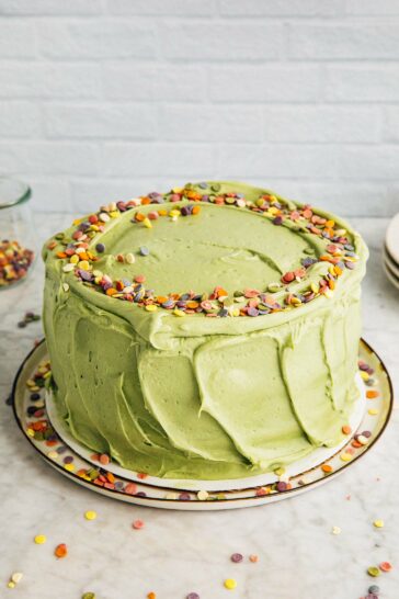 photo of the pistachio pudding layer cake on a marble tabletop against a white brick background