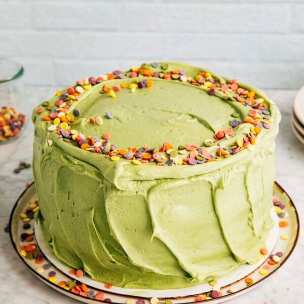 photo of the pistachio pudding layer cake on a marble tabletop against a white brick background