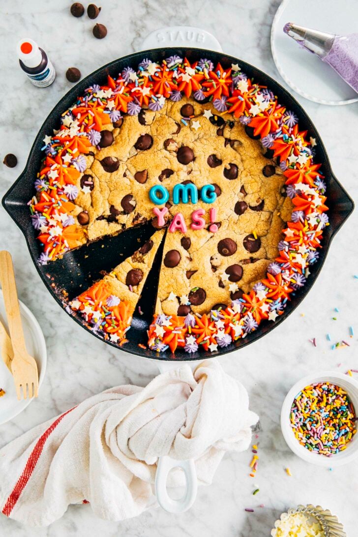photo of my best chocolate chip cookie cake in a white cast iron pan sliced