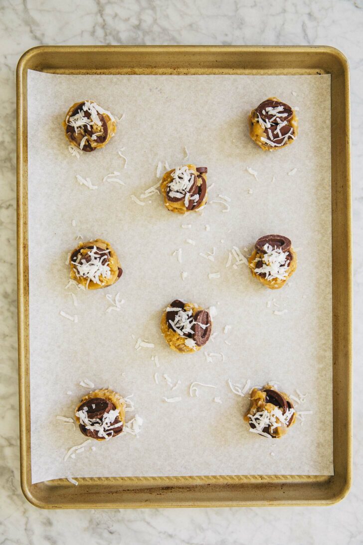 photo of coconut chocolate chip cookie dough balls on gold tray before being baked