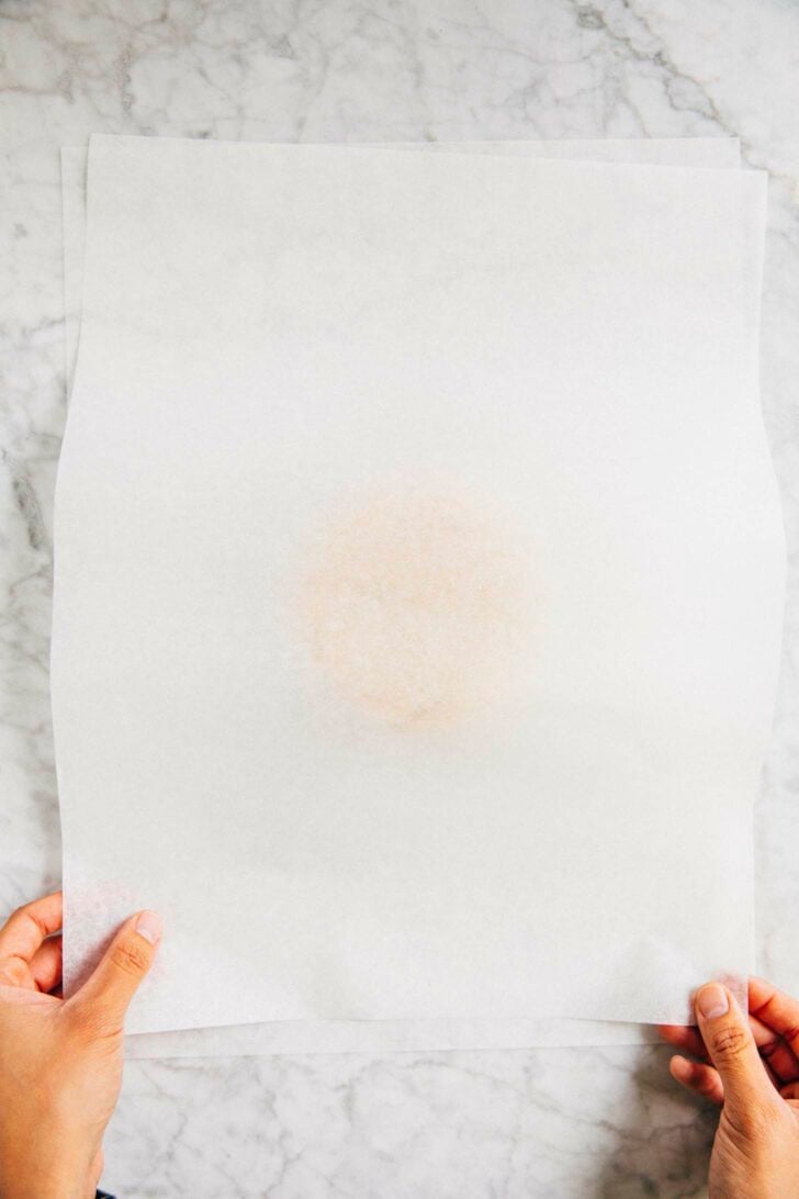 תמונה של מישל מגובה יונק הדבש שמה פיסת נייר פרגמנט על גבי בצק עוגיות הסוכר החתוך