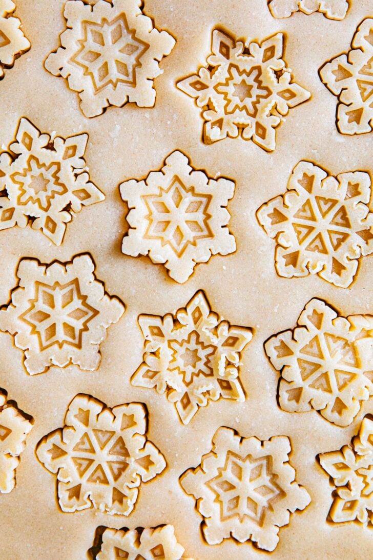 photo of cut out sugar cookie dough rolled and stamped with snowflake cookie cutters