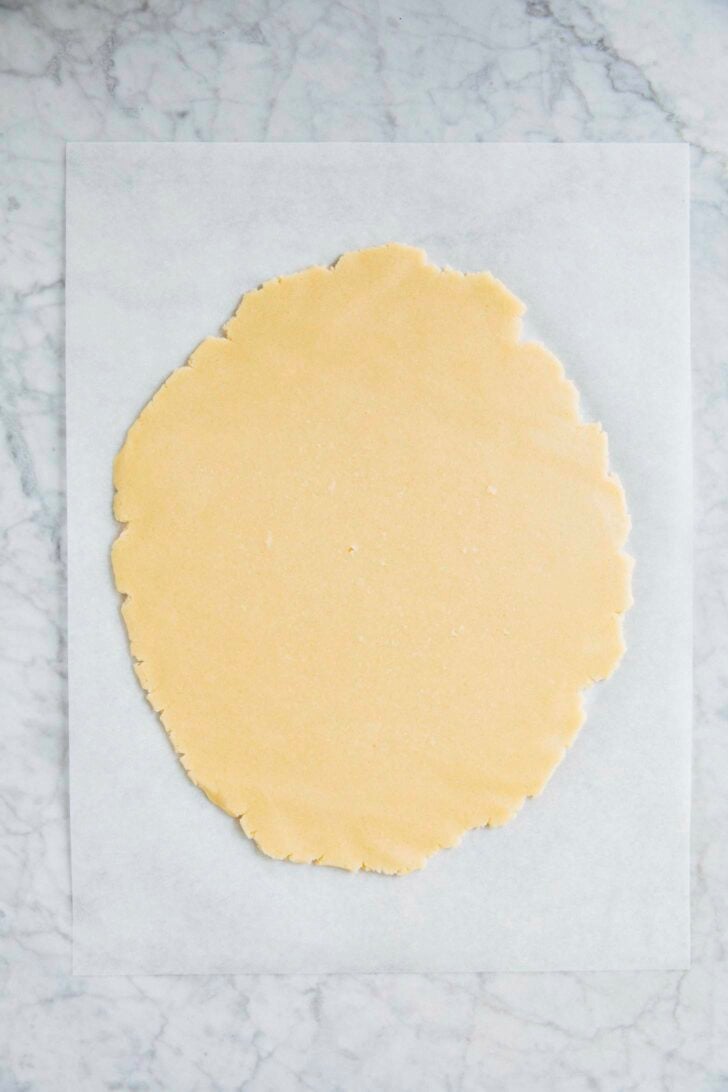 photo of cut out sugar cookie dough rolled out on parchment paper