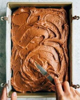 photo of michelle from hummingbird high spreading the chocolate cream cheese frosting on a sheet cake with an offset spatula