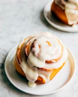 photo of a cinnamon roll with cream cheese frosting on a small white plate