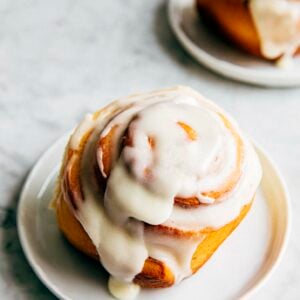 photo of a cinnamon roll with cream cheese frosting on a small white plate