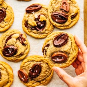 hand picking up rye chooclate chip cookie from a tray