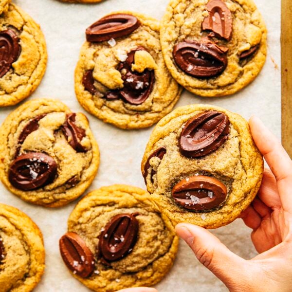 hand picking up rye chooclate chip cookie from a tray