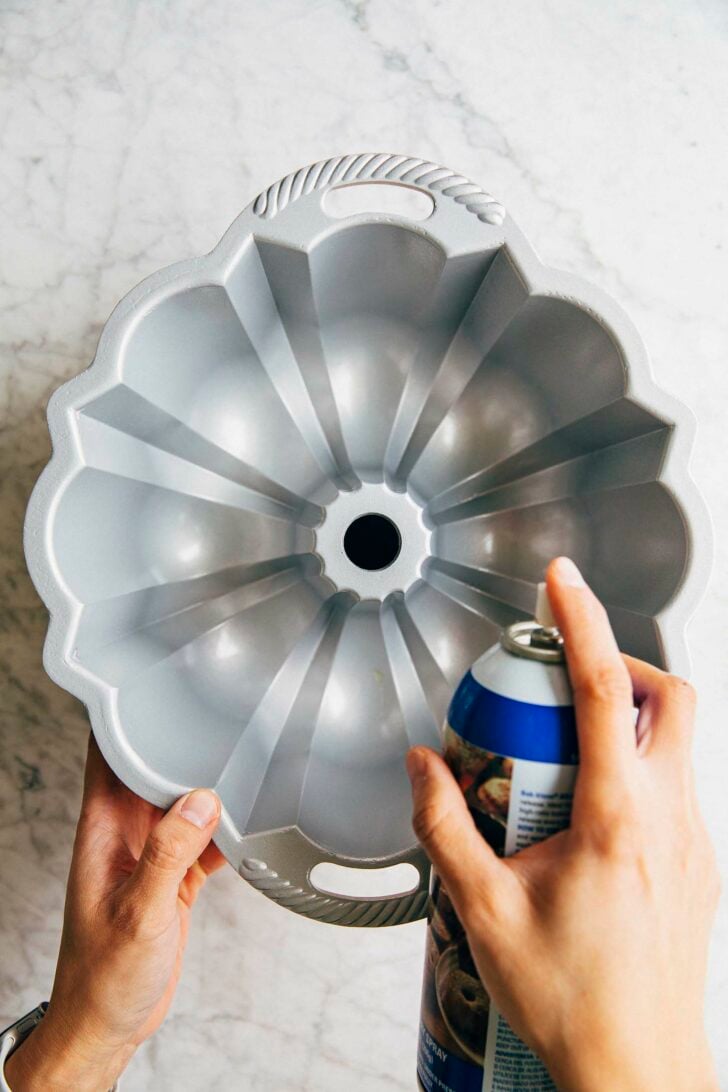 photo of michelle from hummingbird high prepping a bundt pan with baking spray for banana pudding bundt cake