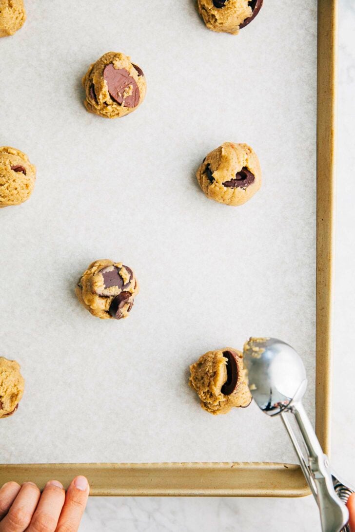 process shot showing how to make rye chocolate chip cookies scooping cookie dough balls on sheet pan
