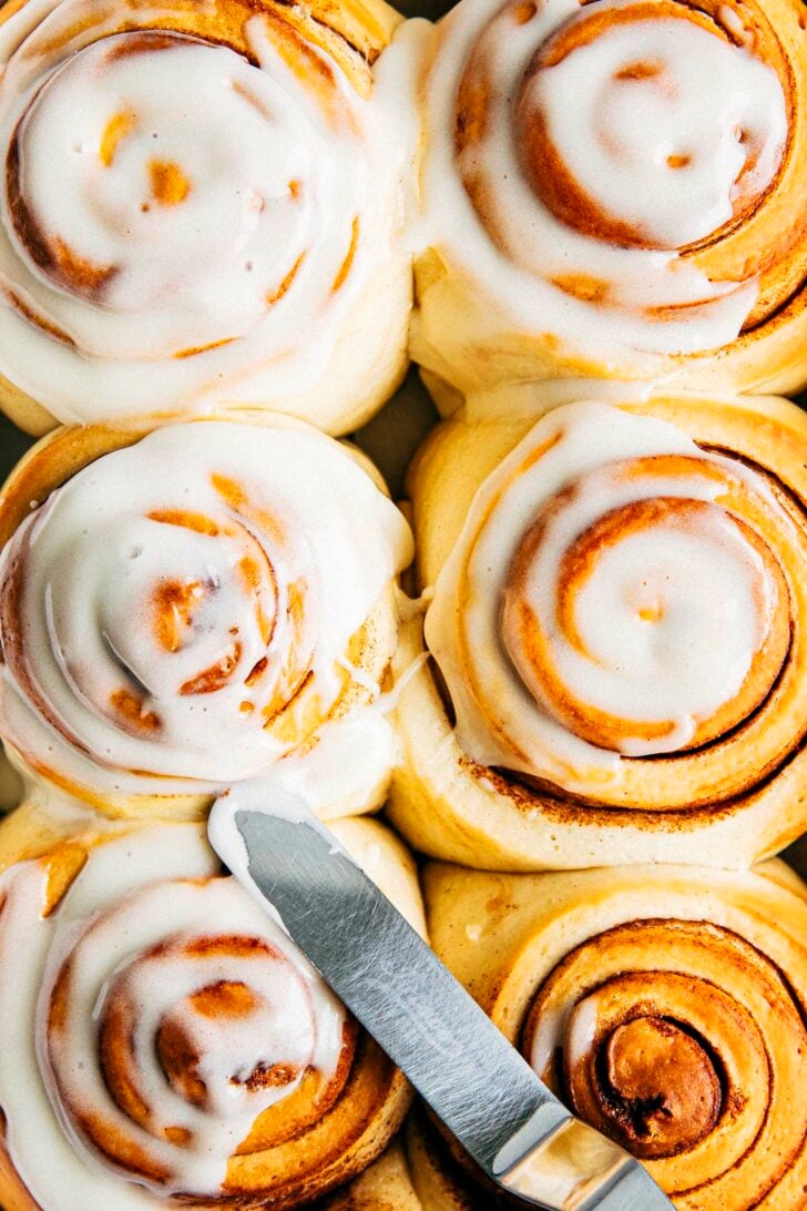 close-up photo of 6 cinnamon rolls about to be frosted with cream cheese frosting for cinnamon rolls