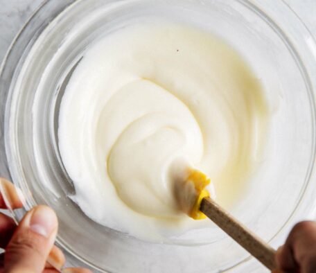 photo of michelle from hummingbird high stirring the cream cheese frosting for cinnamon rolls in a clear glass bowl