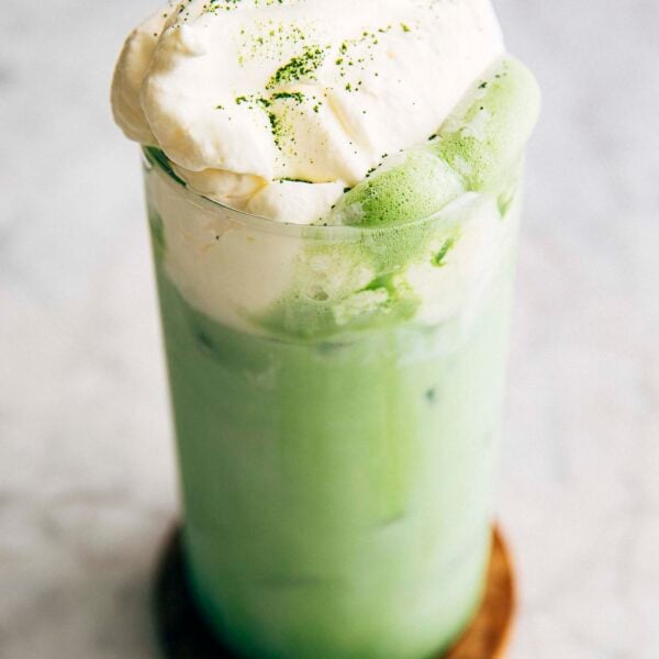 photo of matcha einspanner drink in a tall glass on a wood coaster