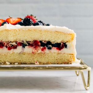 photo of berry chantilly cake sliced showing the layers of cake, fruit, and chantilly cream