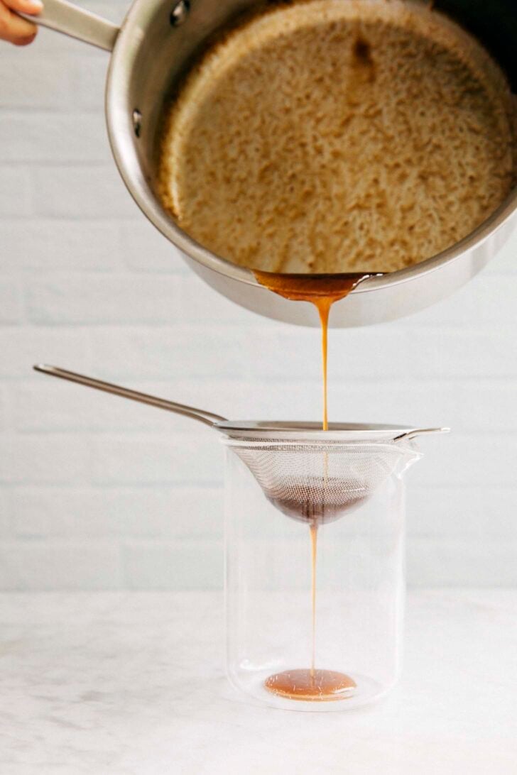 photo of Michelle from hummingbird high straining the pumpkin spice syrup into a liquid measuring cup