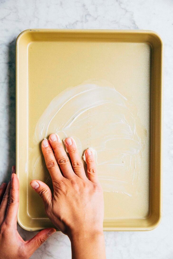 photo of michelle from hummingbird high greasing the sheet pan for the cookie cake