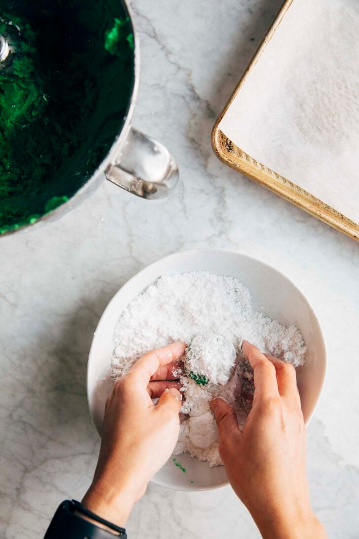 Photo of Michelle from Hummingbird High tossing the cookie dough ball in a bowl of confectioners' sugar